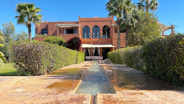 A building with a water feature in front, surrounded by greenery. - Palais Ako Atlas (Marrakech)