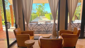 A room with a view of a garden, featuring a seating area with chairs and a small table. - Palais Ako Atlas (Marrakech)