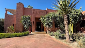 A building with a red facade, a central doorway, and a paved entrance. - Palais Ako Atlas (Marrakech)