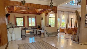 A spacious living area with a high ceiling, large windows, and a mix of seating arrangements. - Palais Ako Atlas (Marrakech)