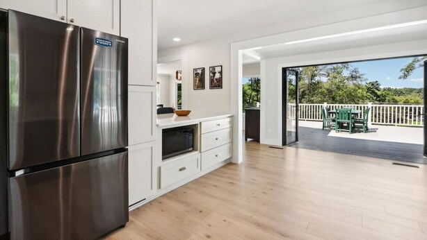 A modern kitchen with stainless steel appliances, white cabinetry, and a view of a deck with outdoor furniture. - Hines Inn - Heart of the Dells! (Wisconsin Dells)