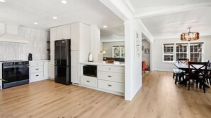 A modern kitchen with white cabinetry, a black refrigerator, and a dining area with a wooden table and chairs. - Hines Inn - Heart of the Dells! (Wisconsin Dells)