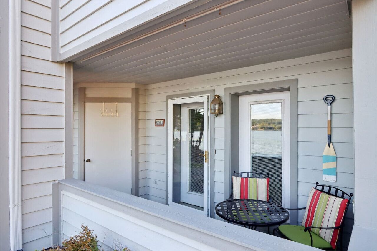 A covered porch with a door, a window, and a table with chairs.