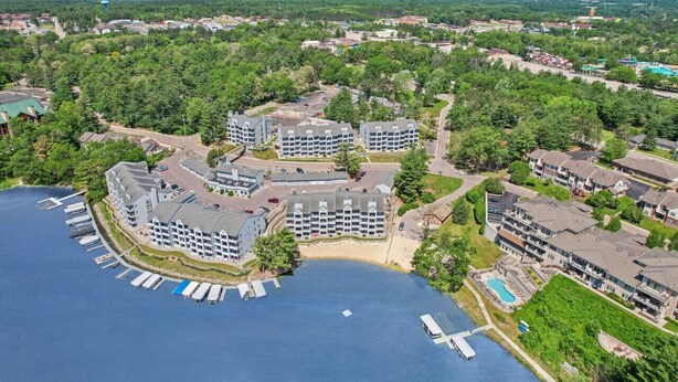 A waterfront hotel with multiple buildings, a dock, and a swimming pool. - Sandy Toes at Lighthouse Cove (Wisconsin Dells)