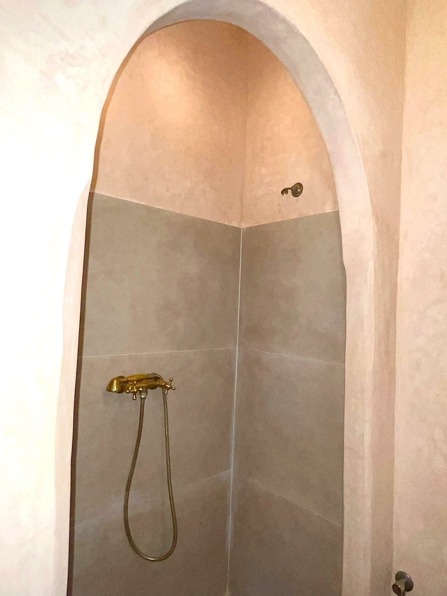 Doccia con arco curvo e soffione a mano.