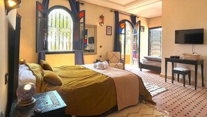 Ein Hotelzimmer mit Bett, Schreibtisch, Fernseher und einem Fenster mit Vorhängen.