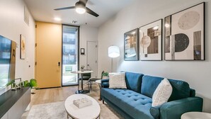 A modern living room with a blue sofa, a white coffee table, and a ceiling fan.