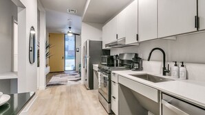 Una cocina moderna con armarios blancos, electrodomésticos de acero inoxidable y un grifo negro.