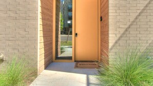 Una puerta con un panel de vidrio, un felpudo y un tapete.
