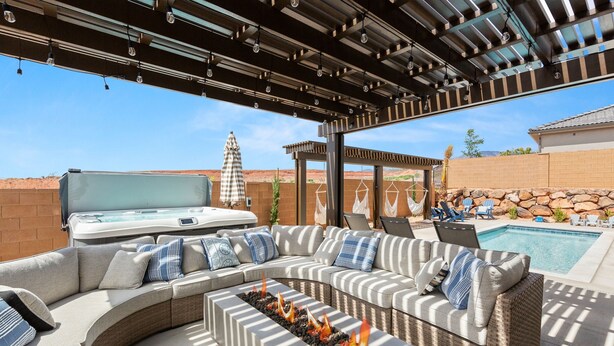 An outdoor patio with a curved sectional sofa, a hot tub, and a fire pit. - Escape to your own private oasis in sunny Washington, Utah! (Washington)