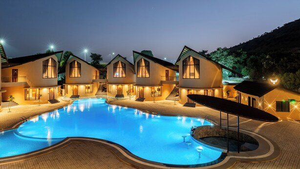 A hotel with a swimming pool, multiple guest rooms, and a landscaped area. - The Qualia Resort Club & Brewery (Udaipur)