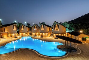 A hotel with a swimming pool, multiple guest rooms, and a landscaped area. - The Qualia Resort Club & Brewery (Udaipur)