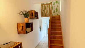 Ein Flur mit einer Holztreppe, Holzwandregalen und einem gefliesten Boden.