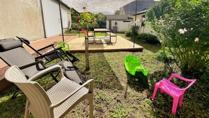 Ein Garten mit einer Terrasse, einem Tisch und Stühlen.