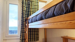 A bunk bed with a headboard, a window with a view, and a checkered curtain. - Spacious 2-room apartment for 6, near shops and slopes (Les Orres)