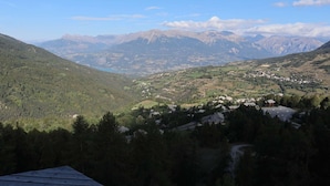 A mountainous landscape with a valley, houses, and a clear sky. - Spacious 2-room apartment for 6, near shops and slopes (Les Orres)