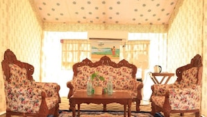 Ein Zimmer mit einer blumigen Sofagarnitur, Holzstühlen, einem Couchtisch und einem gemusterten Teppich.