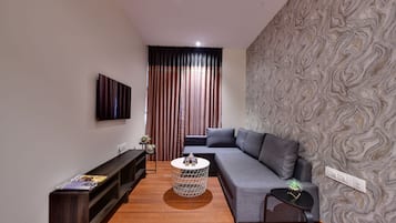 A modern living room with a grey sofa, a round coffee table, and a patterned wallpaper.