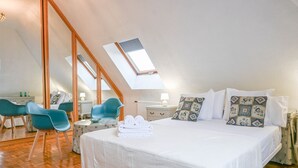 Un dormitorio con una cama grande, un tragaluz, un escritorio con una silla y un espejo.