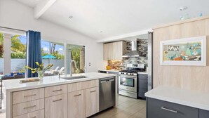 A modern kitchen with a central island, built-in oven, and stainless steel appliances. - Mountain-View Retreat: Pet-Friendly Home with Private Pool (Palm Springs)