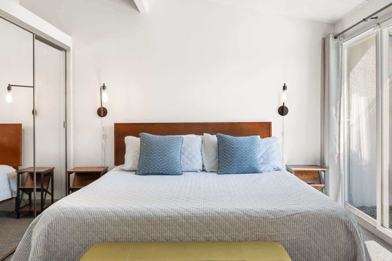A neatly arranged bedroom with a large bed, two bedside tables, and a window providing natural light.