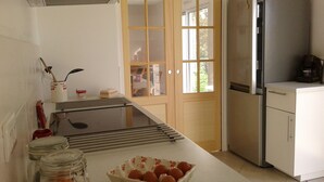 Una cocina con refrigerador, estufa y ventana con vista al exterior.