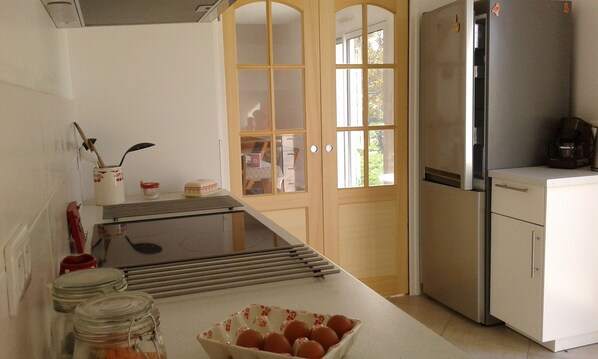 Una cocina con refrigerador, estufa y ventana con vista al exterior.