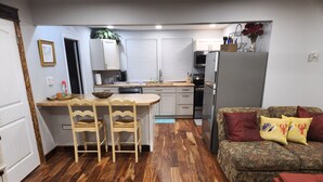 Un espacio habitable compacto con cocina, comedor y un sofá con cojines.