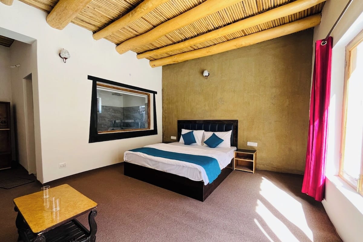 Un dormitorio con cama, mesita de noche y ventana.