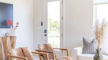 Un salón espacioso con un amplio ventanal, una mesa de centro redonda de madera y dos sillones de cuero.