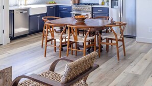 A modern kitchen with dark blue cabinets, stainless steel appliances, and a wooden dining table with chairs. - Elevated Escape | Water Retreat @ Element Ranch (Carmine)