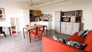 Un espace de vie compact comprenant un coin repas, une kitchenette et un canapé.