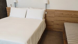 Un lit avec une literie blanche, deux lampes de chevet et une tête de lit en bois.