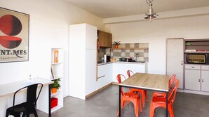 Une cuisine moderne avec des armoires blanches, une table en bois et des chaises orange.