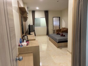 A hotel room with a bed, a desk with a computer, a coffee maker, and a TV. - new sorot house (Pattaya)