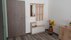 A room with a wooden wardrobe, a mirror, a wooden cabinet, and a vase with flowers. - Vacation apartment in the forest/ central location/ leisure facilities (Neunkirchen)