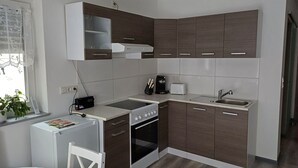 A compact kitchen with a stove, oven, sink, and a small dining area with a chair and table. - Vacation apartment in the forest/ central location/ leisure facilities (Neunkirchen)