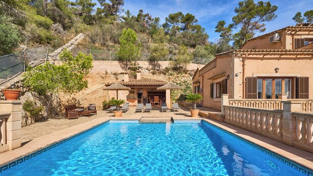A swimming pool with a patio area, surrounded by a stone wall and trees. - Puig de Sa Figuera Country House with Private Pool and Panoramic Views for 8 pax (Felanitx)