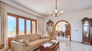 A spacious living room with a beige sofa, a wooden coffee table, and a chandelier. - Puig de Sa Figuera Country House with Private Pool and Panoramic Views for 8 pax (Felanitx)