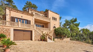 A two-story house with a stone facade, a balcony, and a garage. - Puig de Sa Figuera Country House with Private Pool and Panoramic Views for 8 pax (Felanitx)