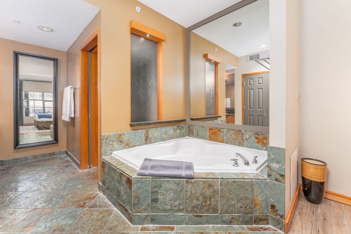 Ein modernes Badezimmer mit einer großen Badewanne, einem Spiegel und einer Holztür.