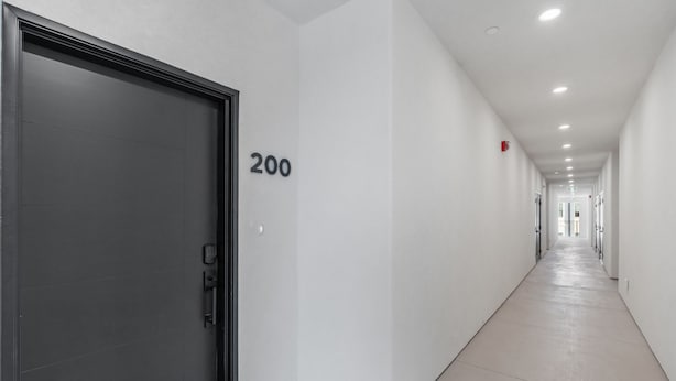 A corridor with a closed door marked '200', white walls, and a tiled floor.