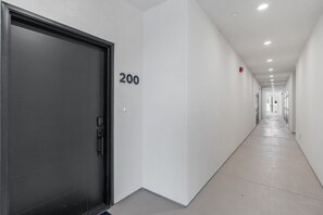 A corridor with a closed door marked '200', white walls, and a tiled floor.
