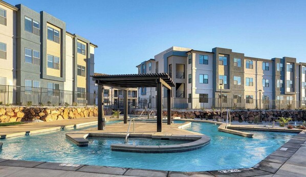 A modern apartment building with a swimming pool and a covered outdoor seating area.