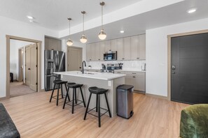 A modern kitchen with a central island, stainless steel appliances, and bar stools.