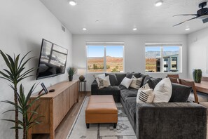 A modern living room with a large flat-screen TV, a dark gray sofa, and a wooden cabinet.