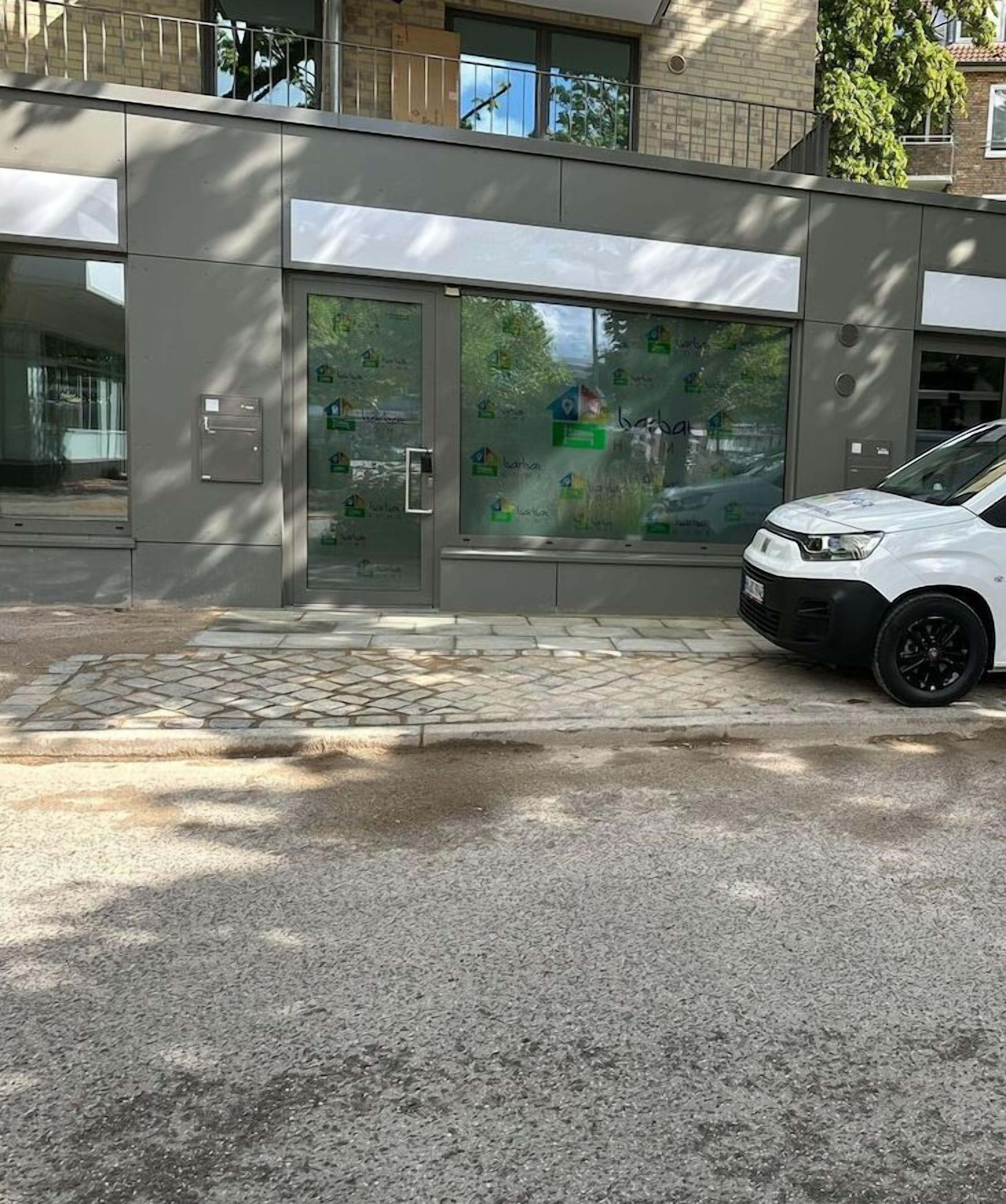 Modernilla designilla varustettu rakennus, jossa on lasinen sisäänkäynti ja edessä päällystetty alue.