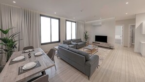 A modern living room with a grey sofa, a dining table set for four, and a flat-screen TV. - Mabaat - Al Rimal - 565 (Riyadh)