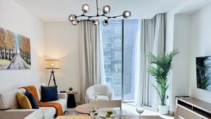 A modern living room with a dining area, a sofa, a coffee table, and a chandelier. - Modern 2 Bed with Stunning Views (Dubai)