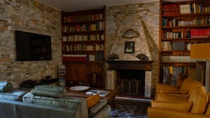 A cozy living room with a fireplace, bookshelves, a sofa, and a television.